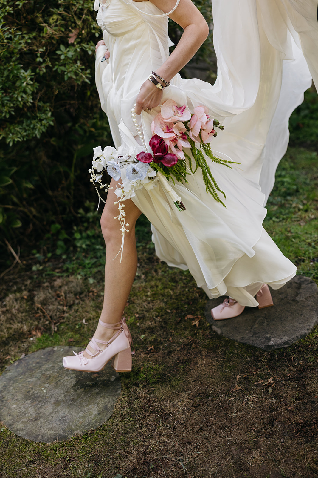 Bride walking through the grounds , holding a colorful bouquet during a fashion-forward Catskills wedding.