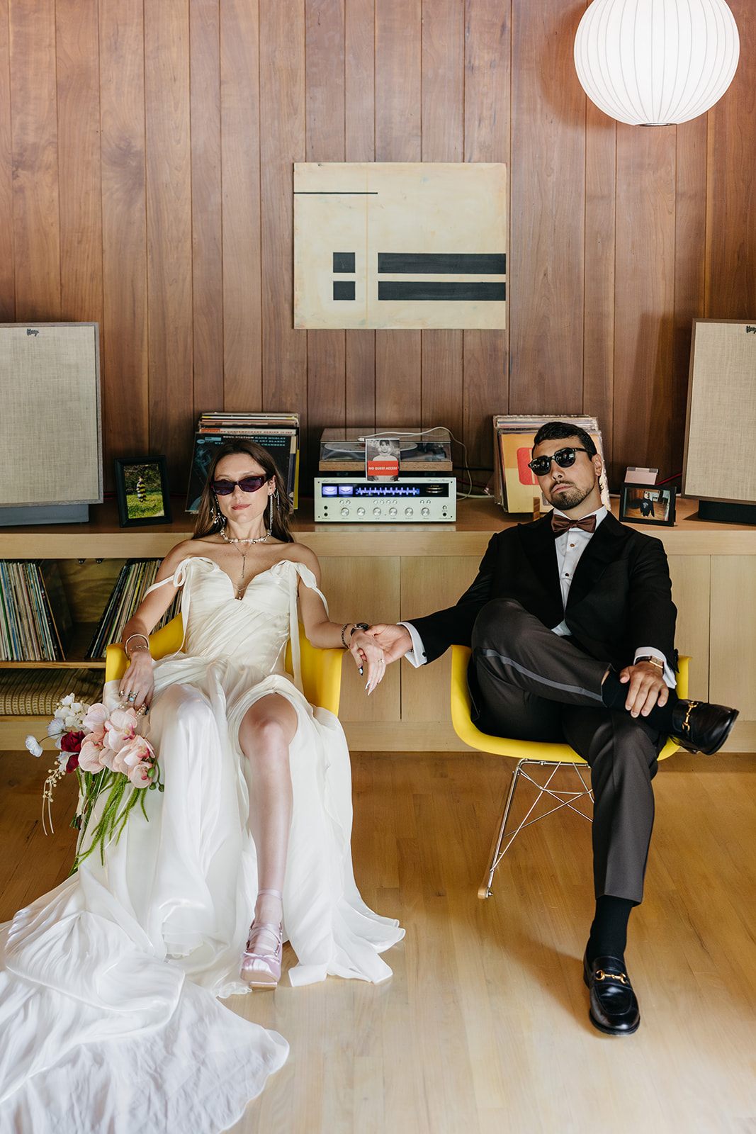 Bride and groom lounging indoors at The Mod House in Ellenville, NY with retro decor and fashion-forward wedding style.