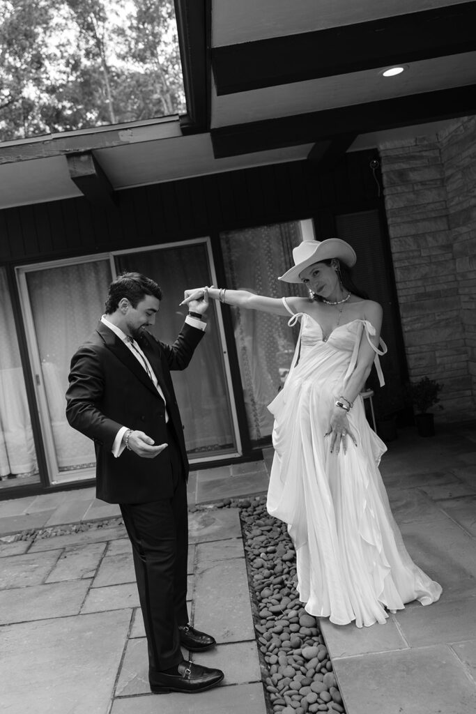Bride and groom dancing together outside The Mod House in Ellenville, NY, showing playful energy and fashion-forward wedding style.