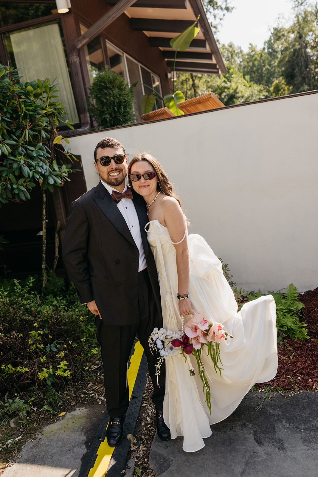 Fashion-forward bride and groom posing outside The Mod House in Ellenville, NY with mid-century modern architecture in the background.
