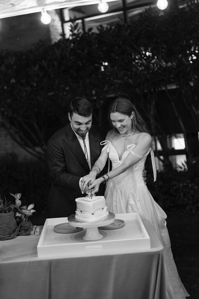 Black and white photo of the couple cutting their wedding cake during an intimate reception at The Mod House in Ellenville, NY.