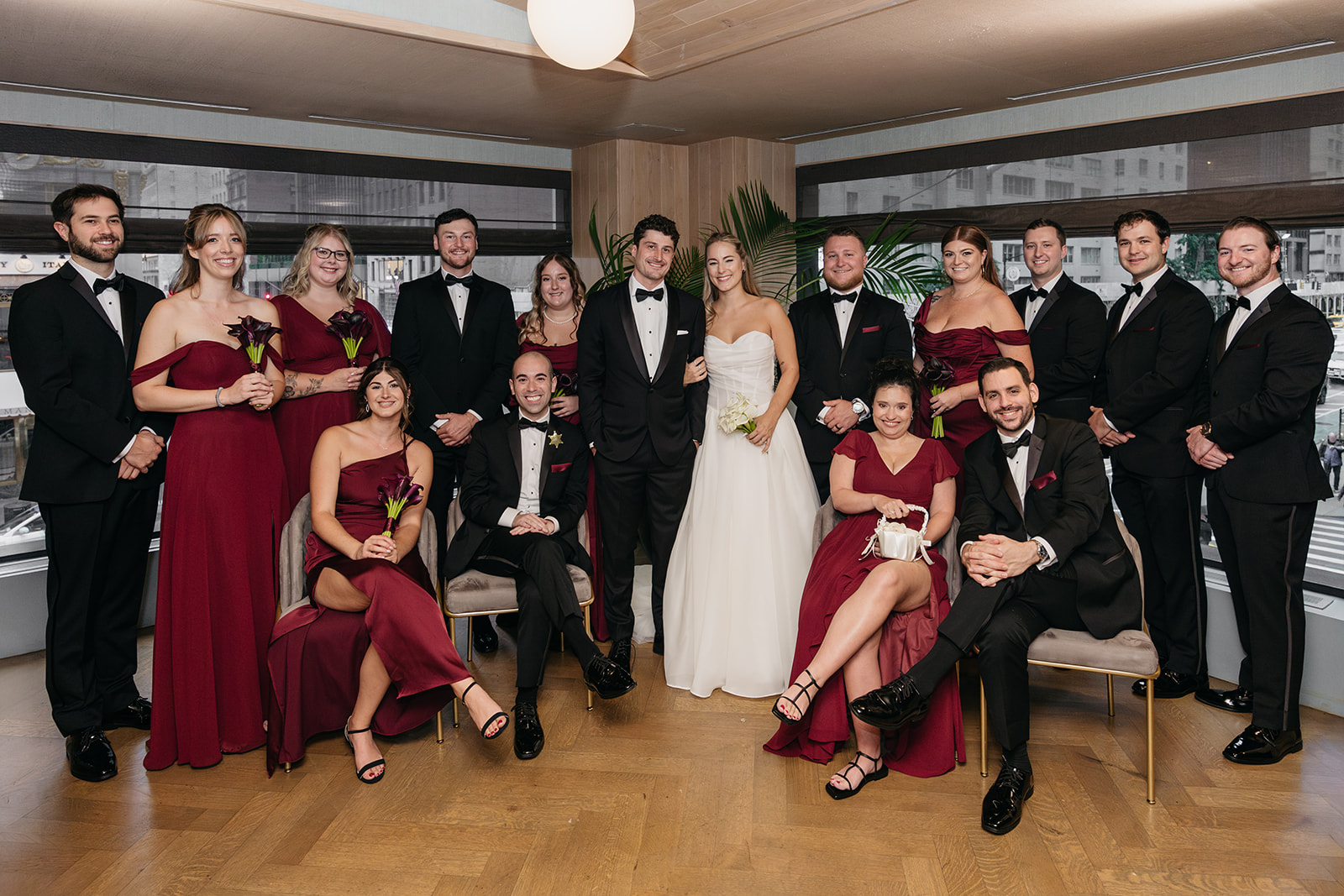 Large wedding party group photo inside Acadia NYC featuring seated and standing guests in a modern, intimate restaurant setting.