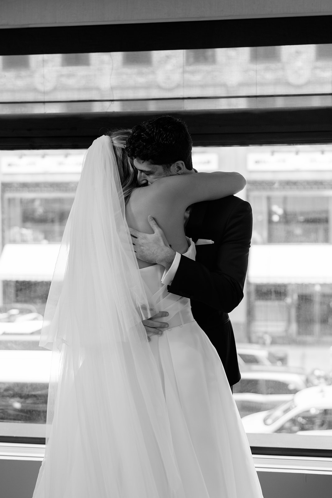Emotional black and white wedding portrait of the couple embracing indoors near a window during their Acadia NYC wedding.