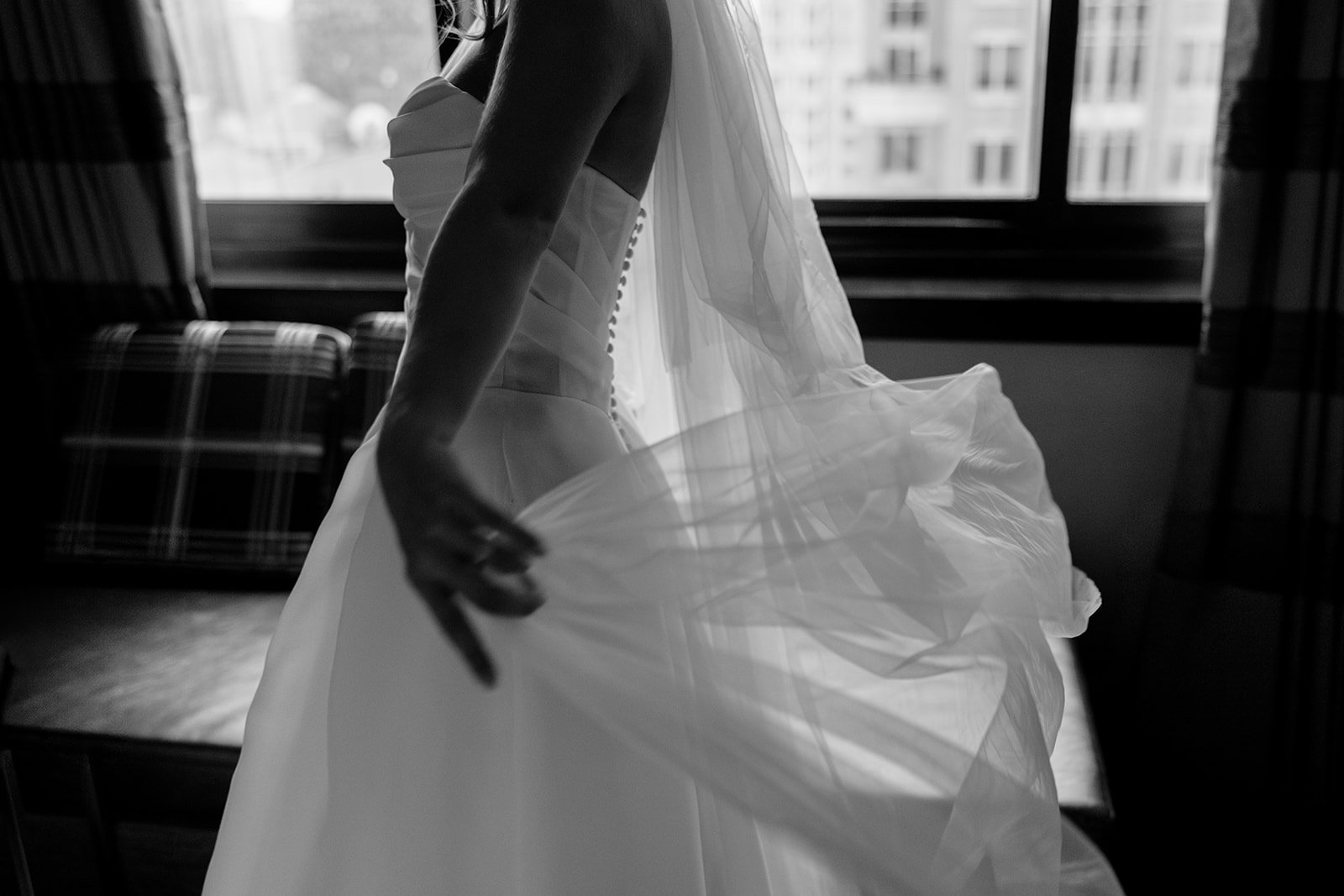Bride adjusting her wedding dress indoors with soft window light during an intimate Acadia NYC wedding moment.