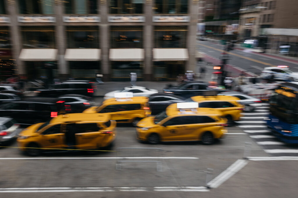 Motion-blurred New York City traffic scene with yellow taxis capturing the energy of a rainy Manhattan wedding night.