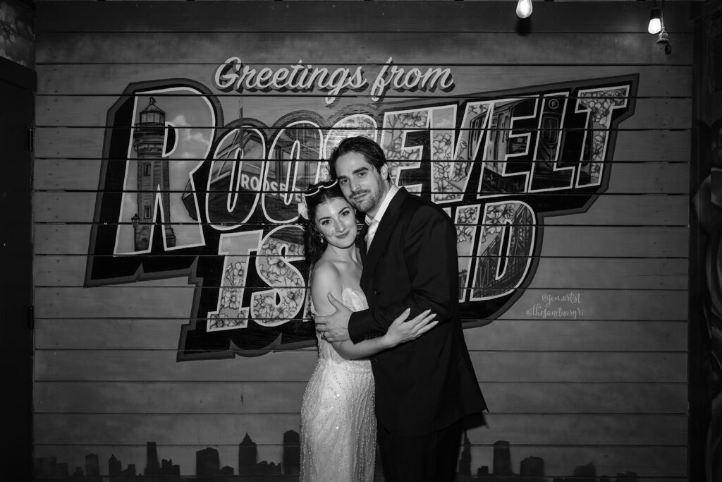 black and white of the bride and groom embracing in front of the roosevelt island sign
