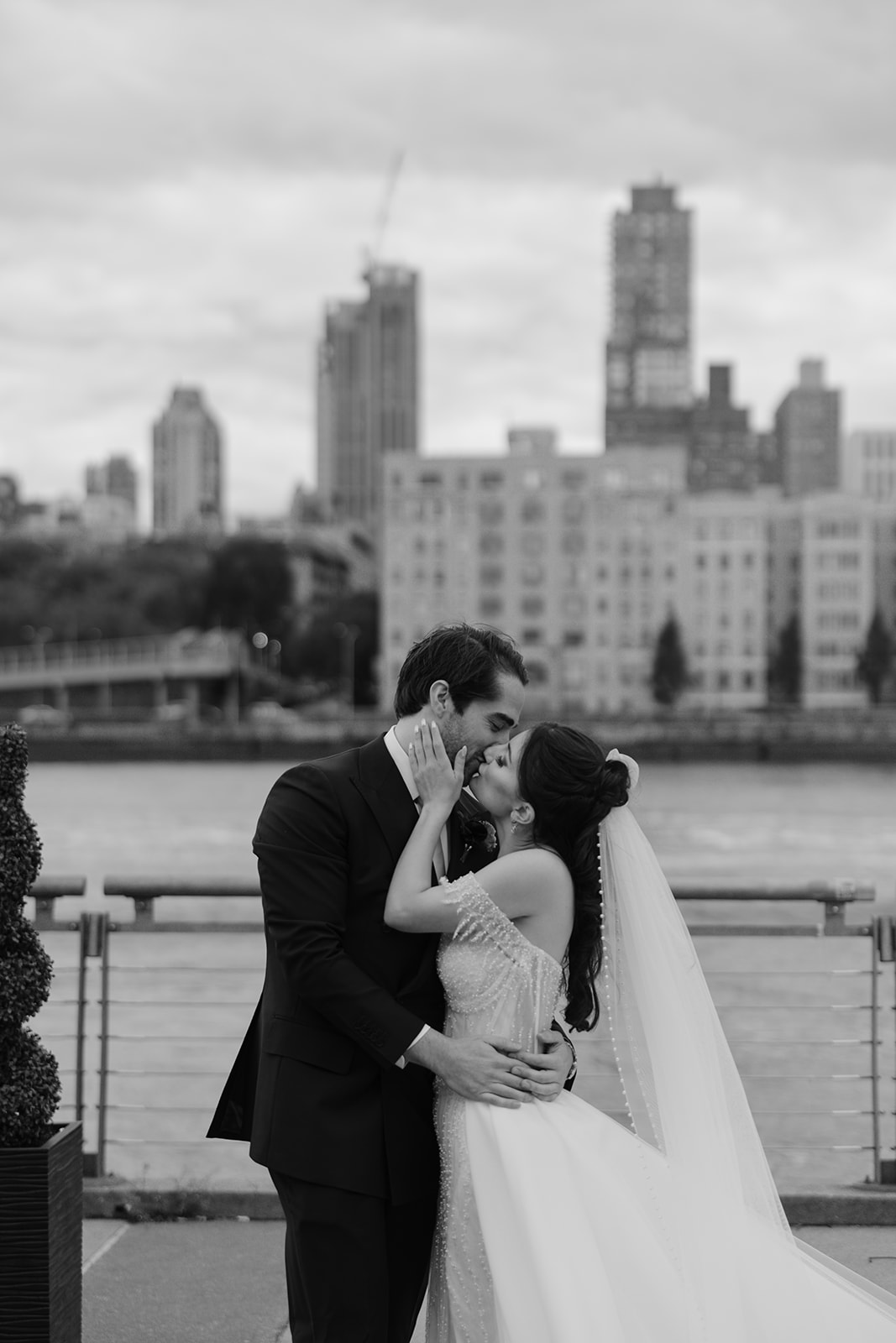 bride and groom kissing with a skyline view of the Roosevelt Island in New York City