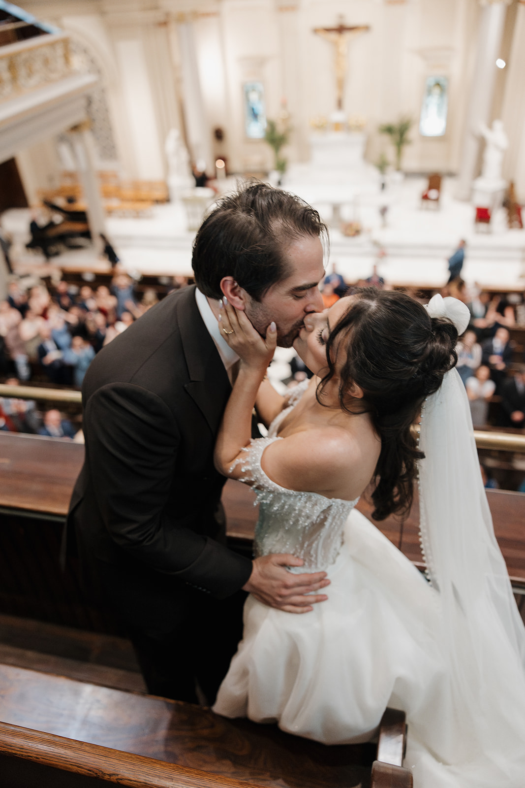Bride and groom kissing above their wedding guest at the at St. Francis de Sales Roman Catholic Church