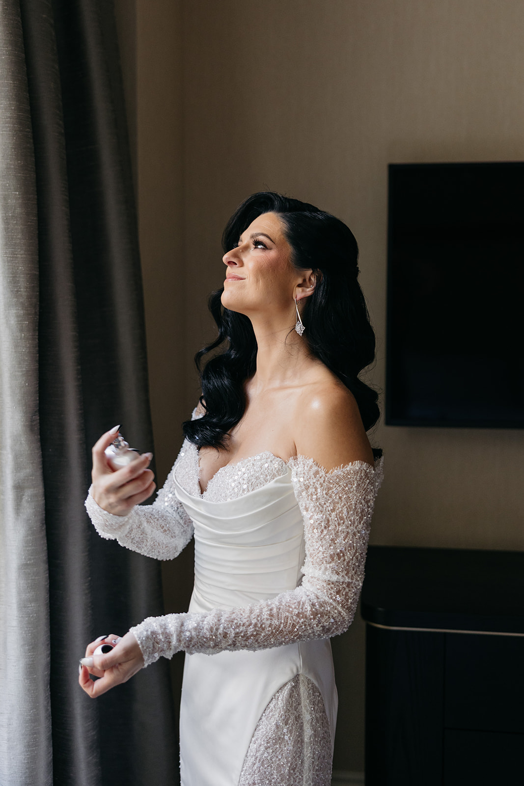 Bride applying perfume while getting ready in a hotel suite before the Chicago Union Station wedding