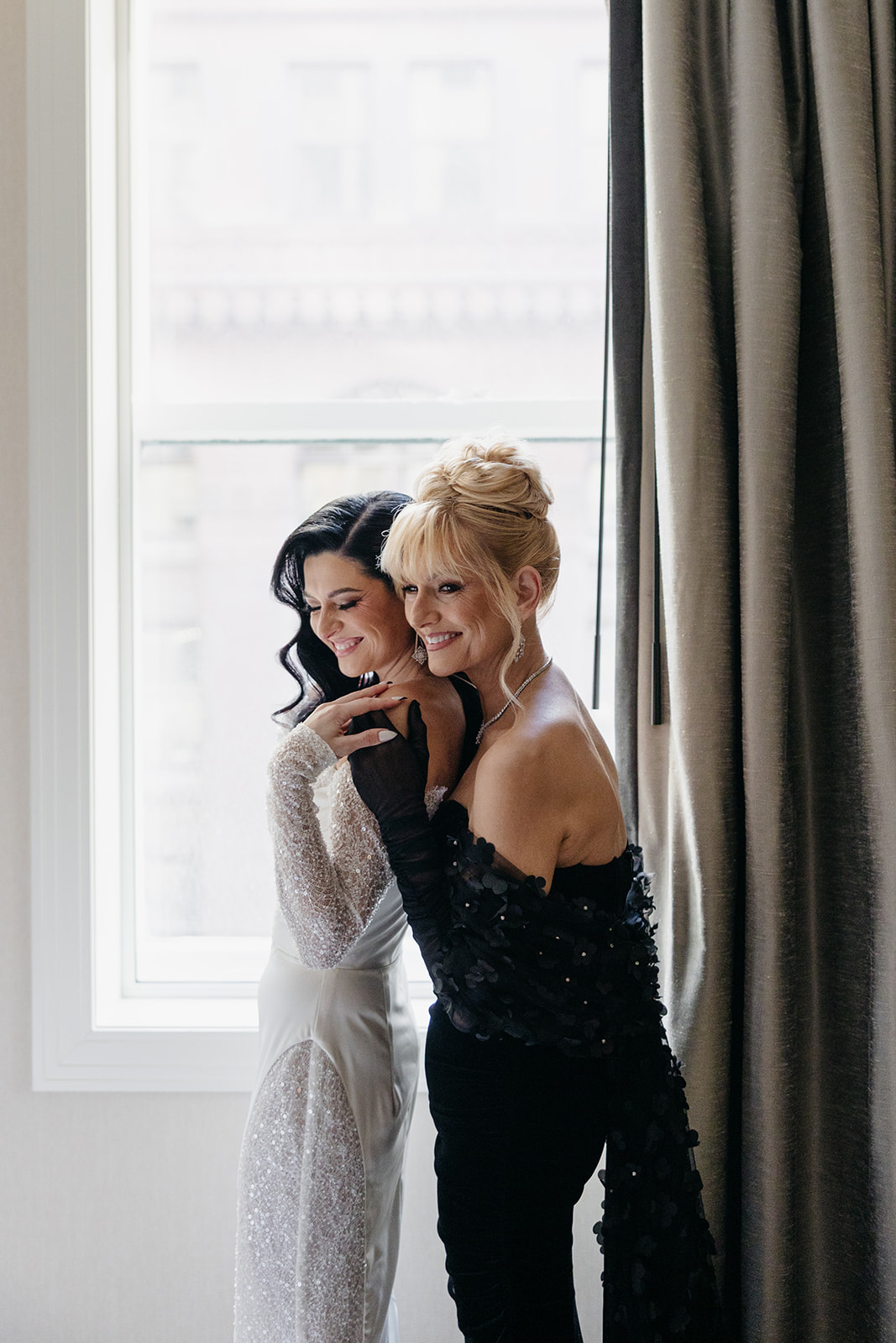 Bride hugging her mother by the window while getting ready on the wedding morning in Chicago