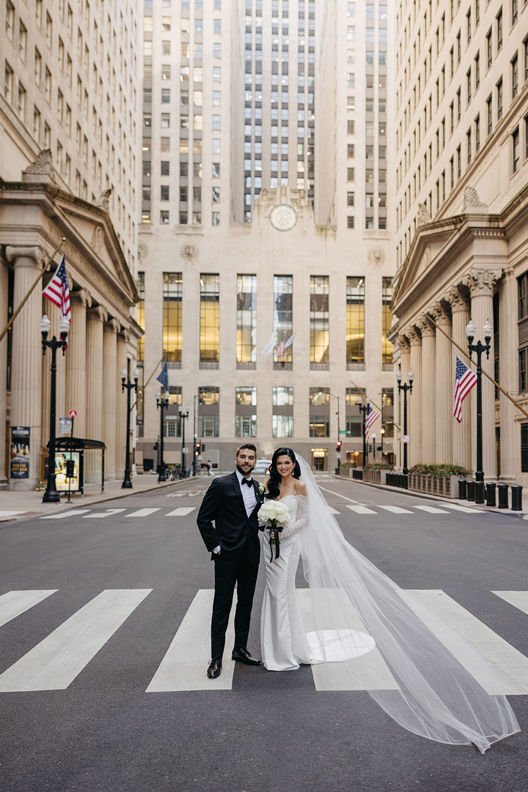 Bride and groom standing in the street in downtown Chicago with the Chicago Board of Trade building behind them