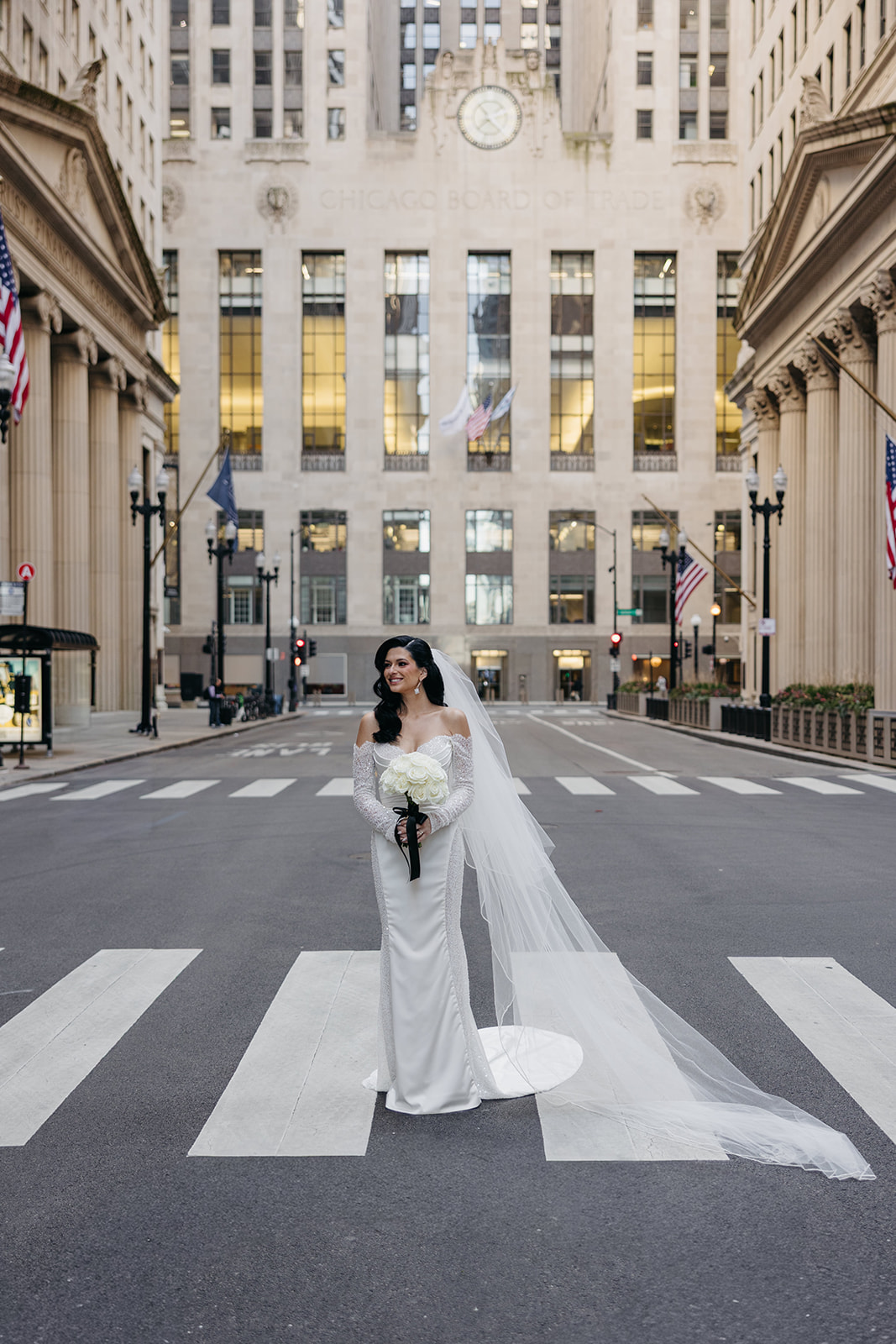 Bride standing in the street in downtown Chicago with the Chicago Board of Trade building behind her