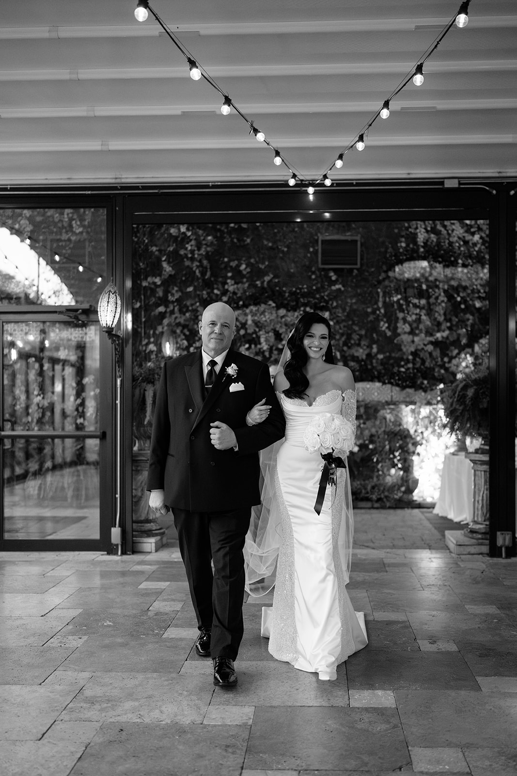 Bride walking down the aisle with her father during a romantic indoor wedding ceremony