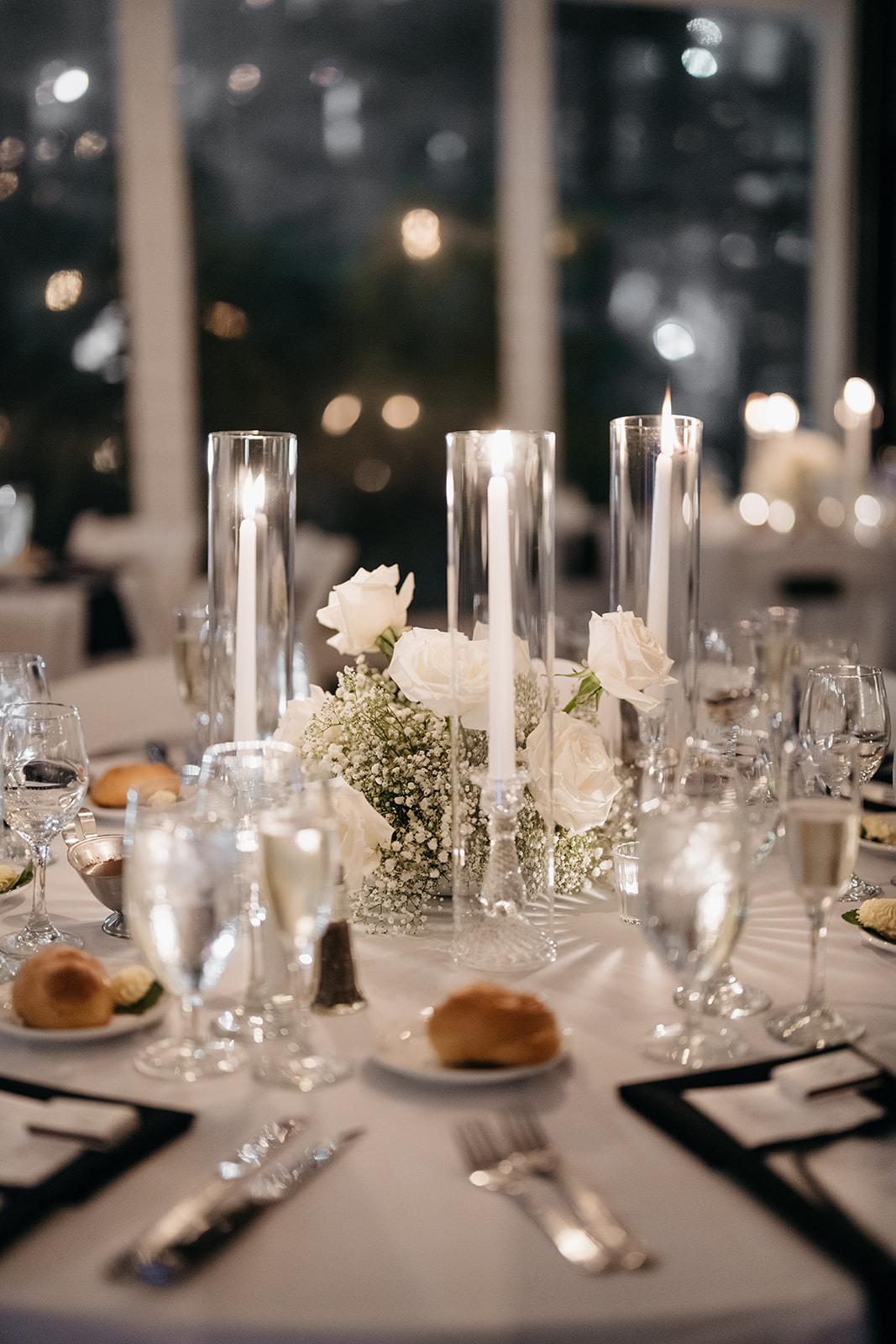 Wedding reception table centerpiece with white roses, candles, and glassware at Galleria Marchetti