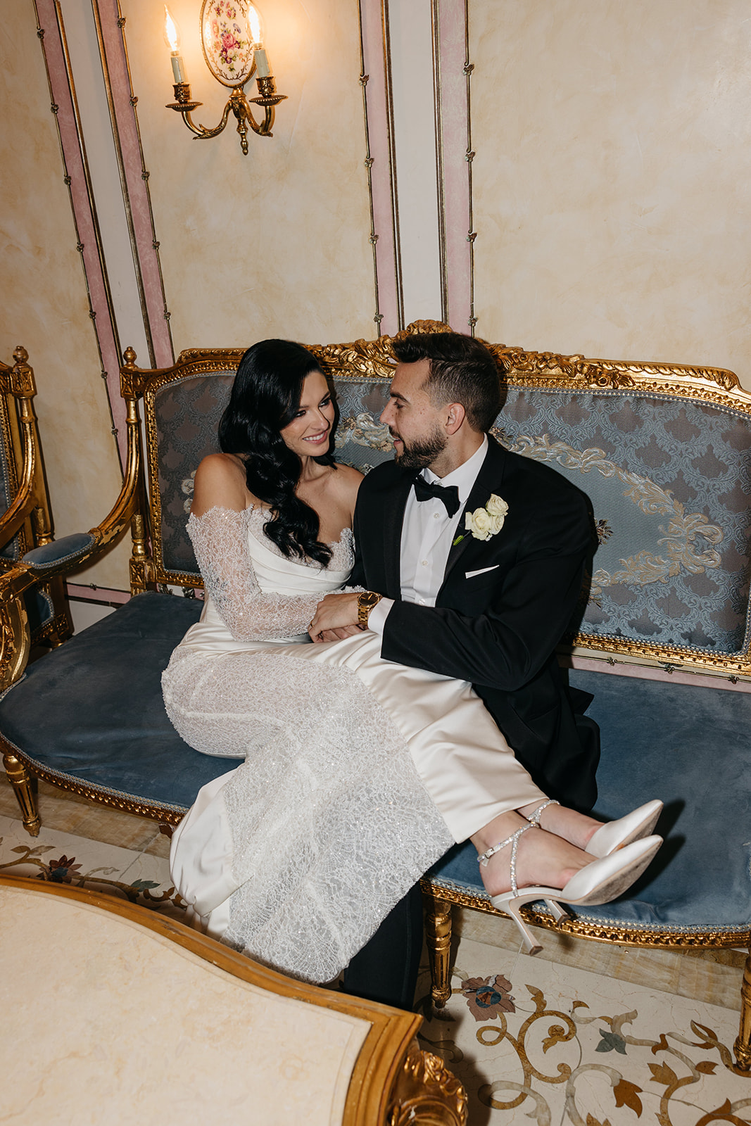Bride and groom sitting together on an ornate vintage sofa during their Chicago wedding reception portraits