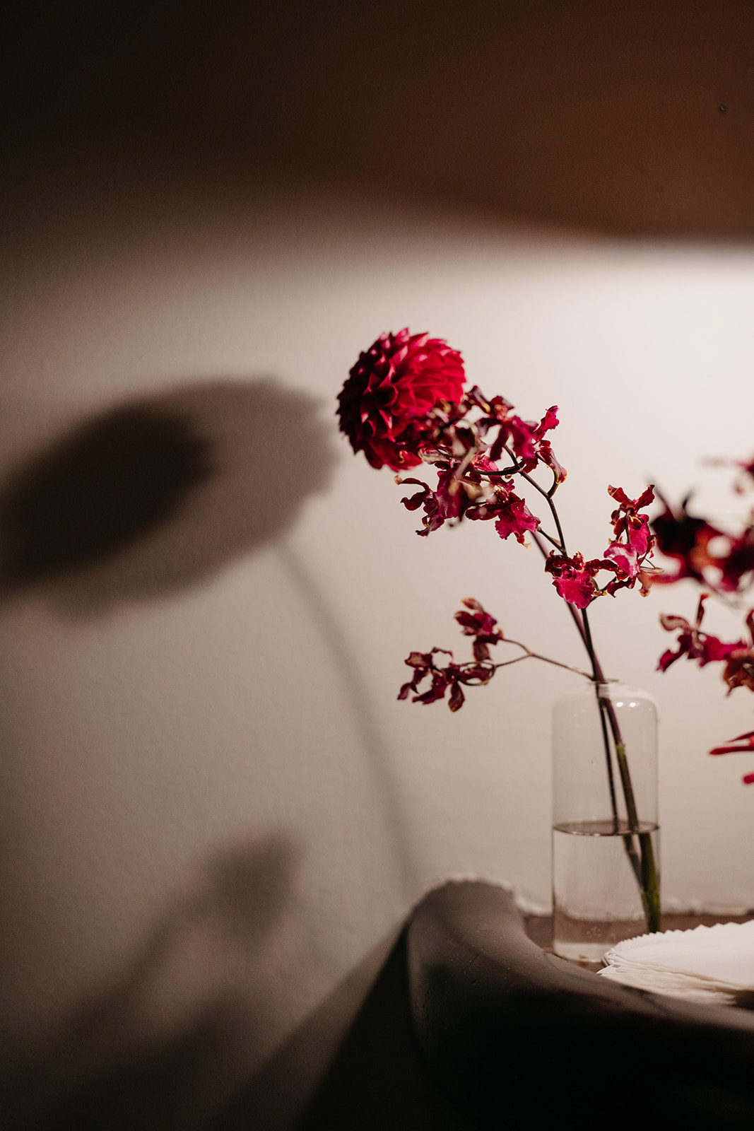 Moody red floral arrangement in glass vase with soft lighting, romantic wedding detail inspiration