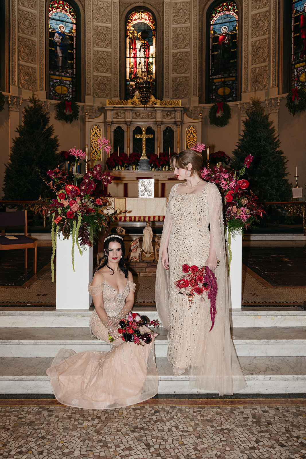 Brides in champagne beaded gowns posing at altar with dramatic florals at Montauk Club NYC wedding