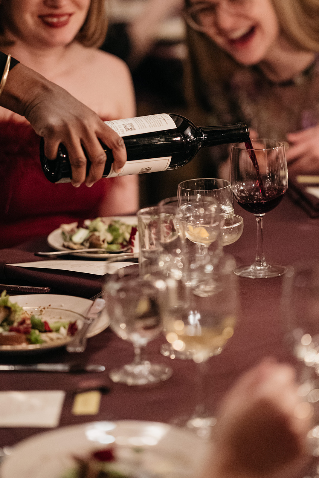 Guests enjoying dinner while pouring red wine at elegant Brooklyn wedding reception