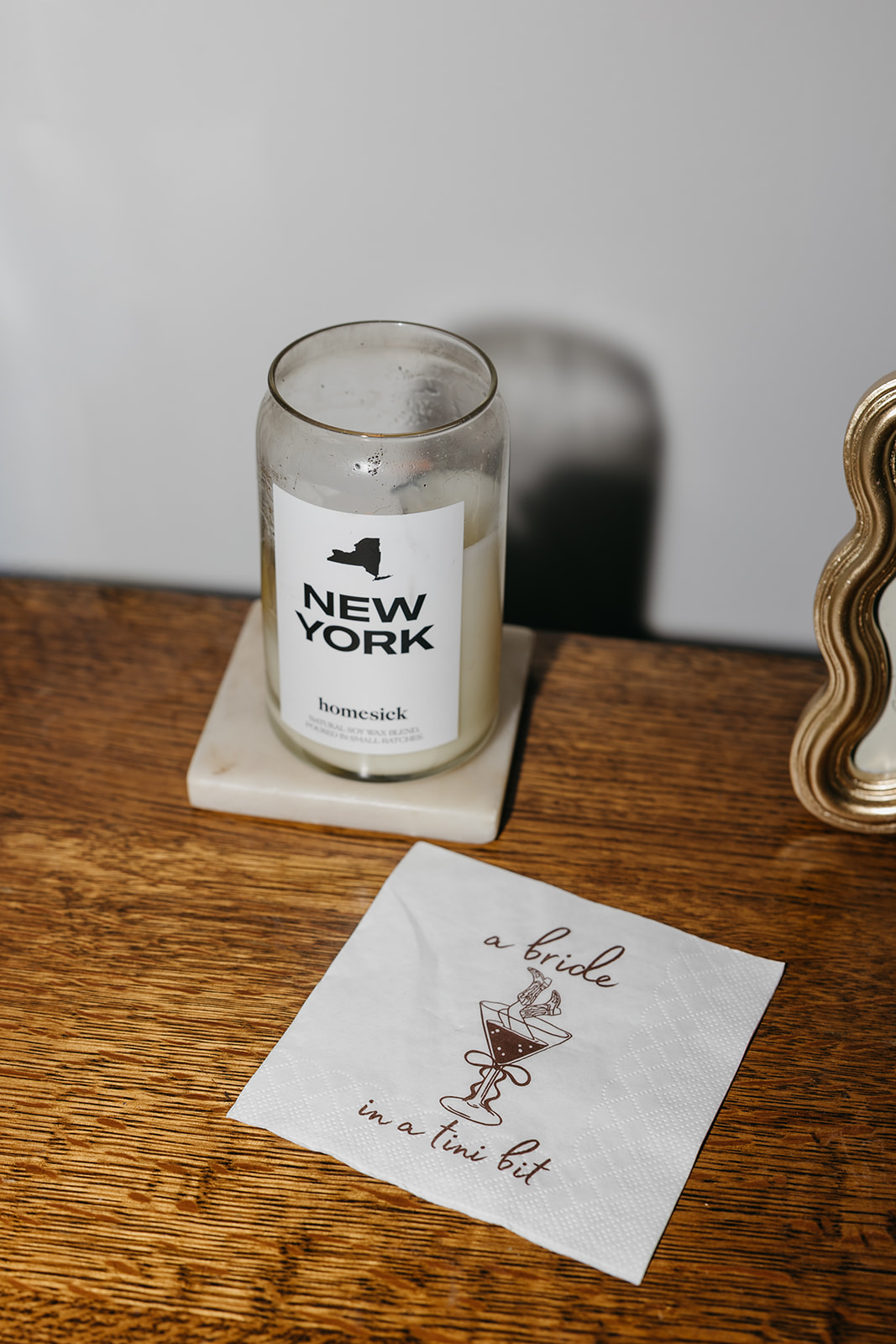 New York themed candle and wedding detail flat lay with napkin reading a bride in a tini bit