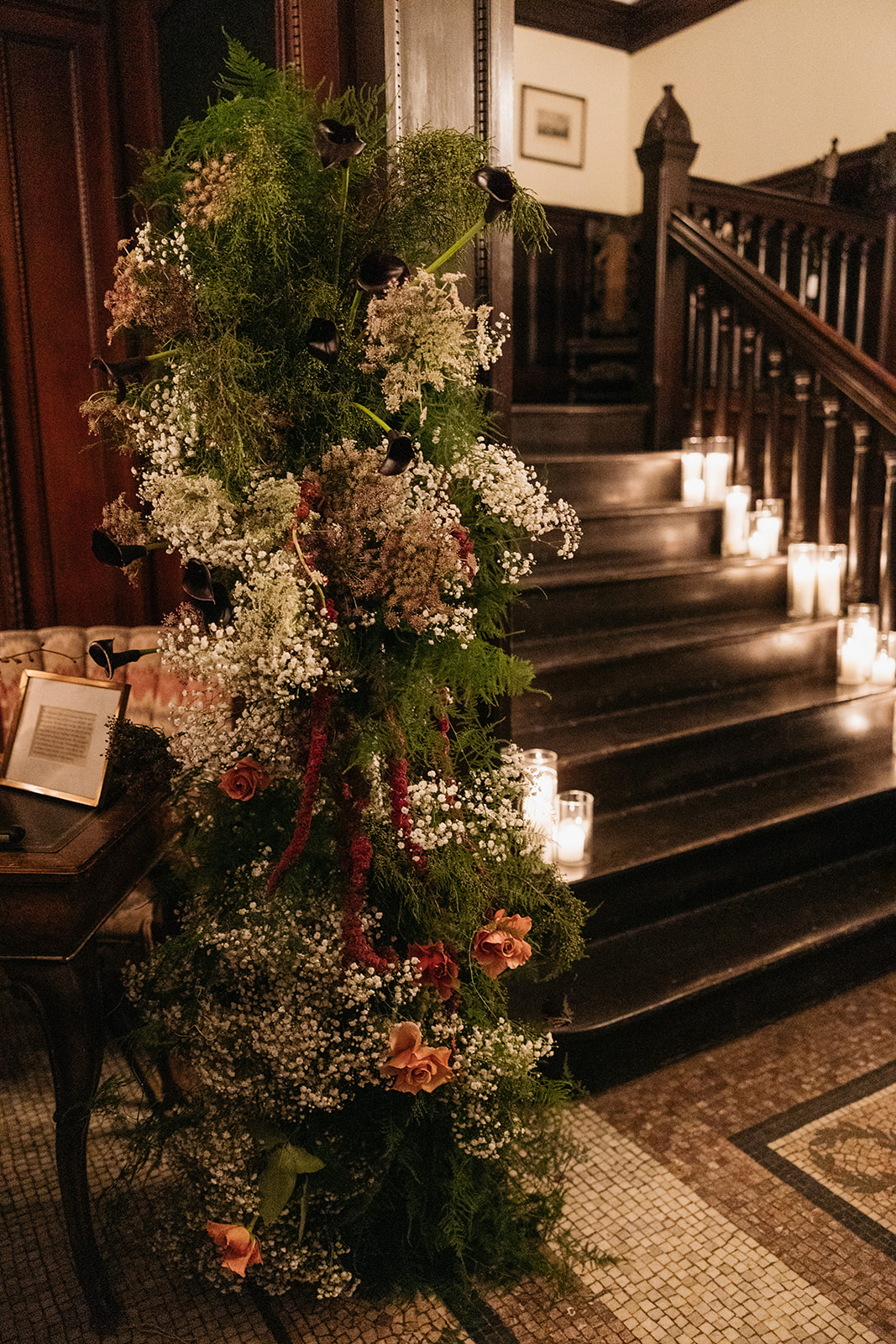 Dramatic floral installation on staircase with candles at Montauk Club NYC wedding venue