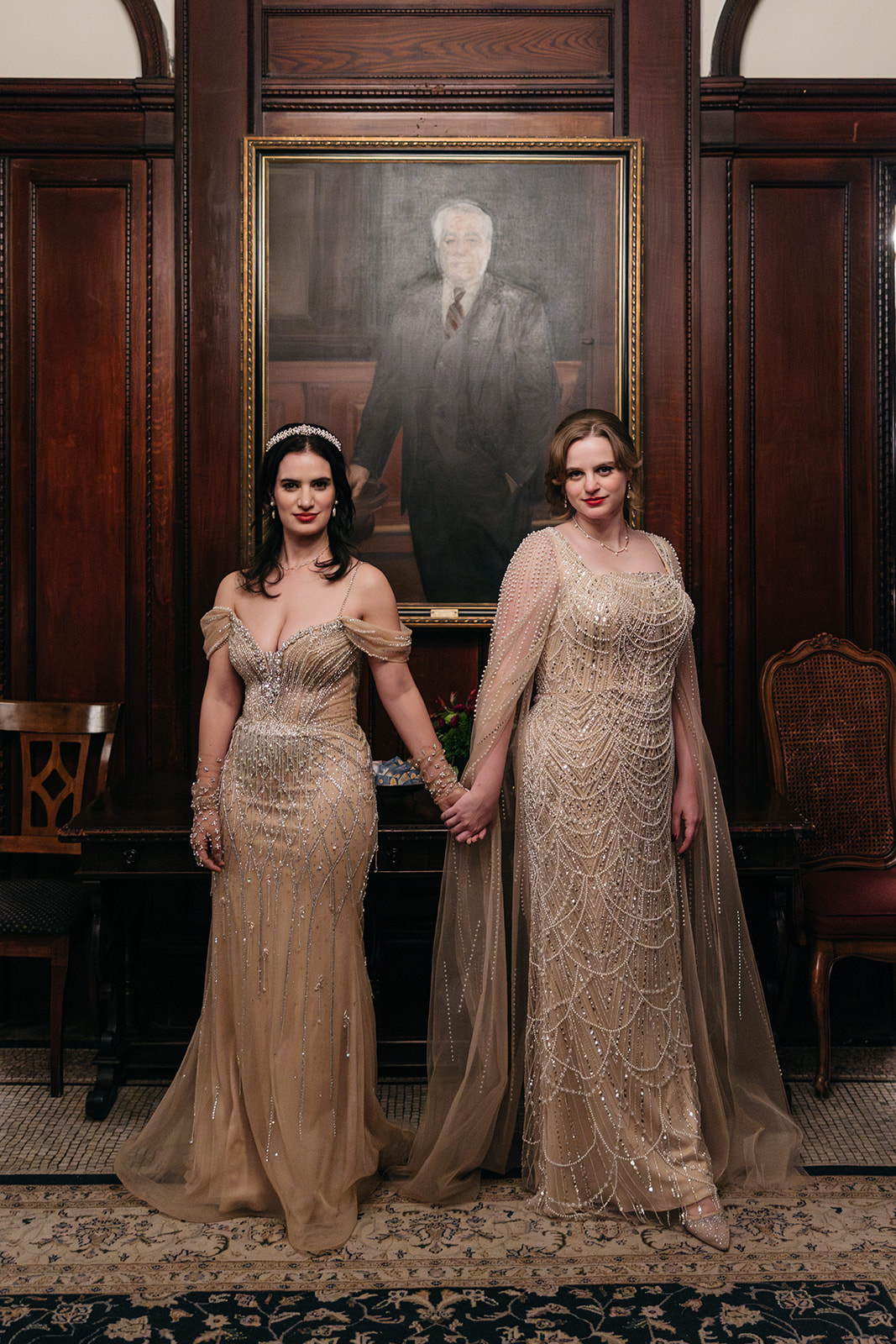 Brides holding hands in beaded gowns inside historic Brooklyn wedding venue