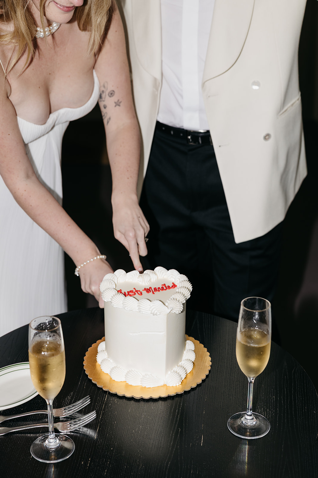 Couple cutting wedding cake with champagne glasses, classic reception moment at San Diego wedding venue