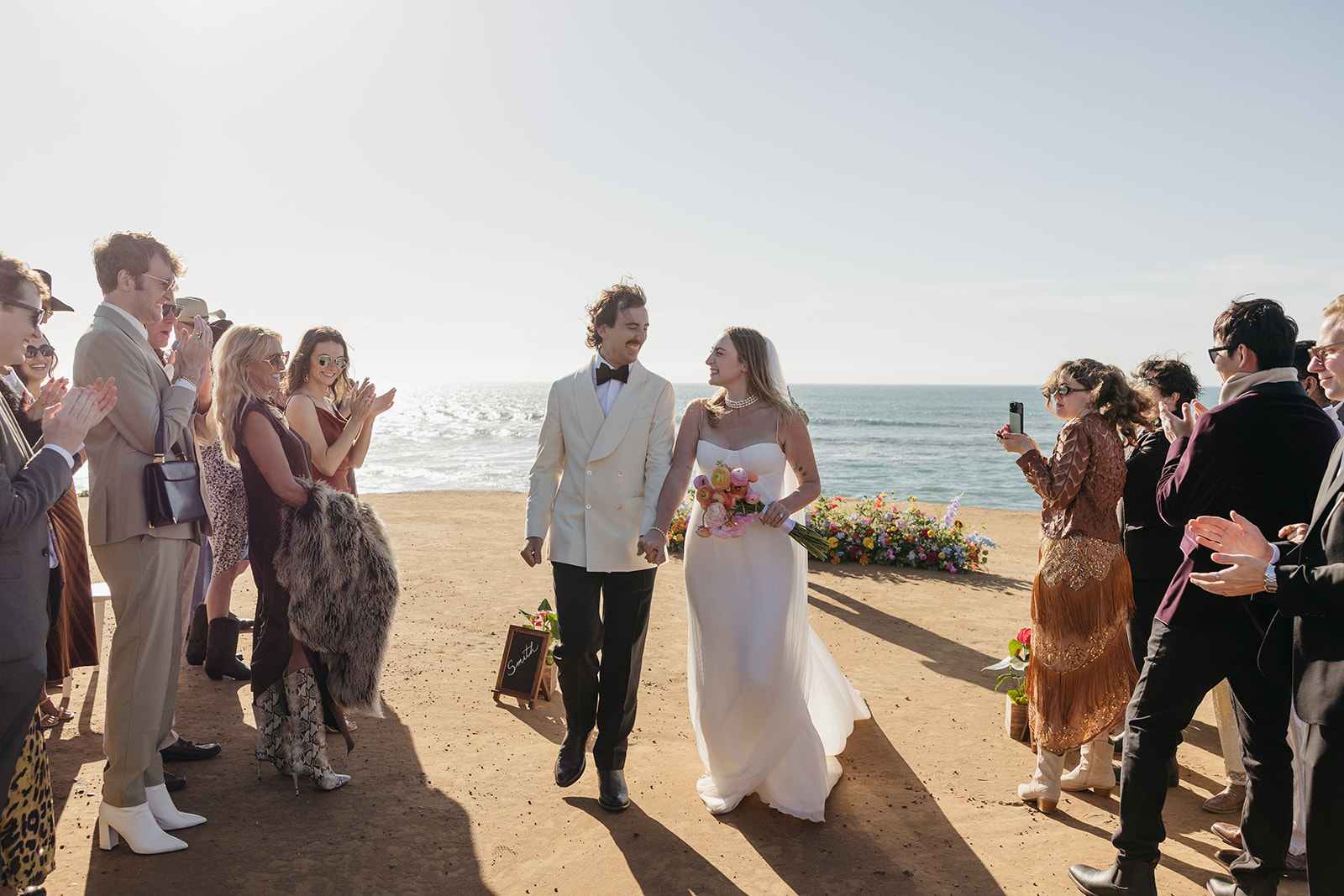 Newlyweds walking down the aisle surrounded by guests with ocean backdrop at the pearl san diego wedding