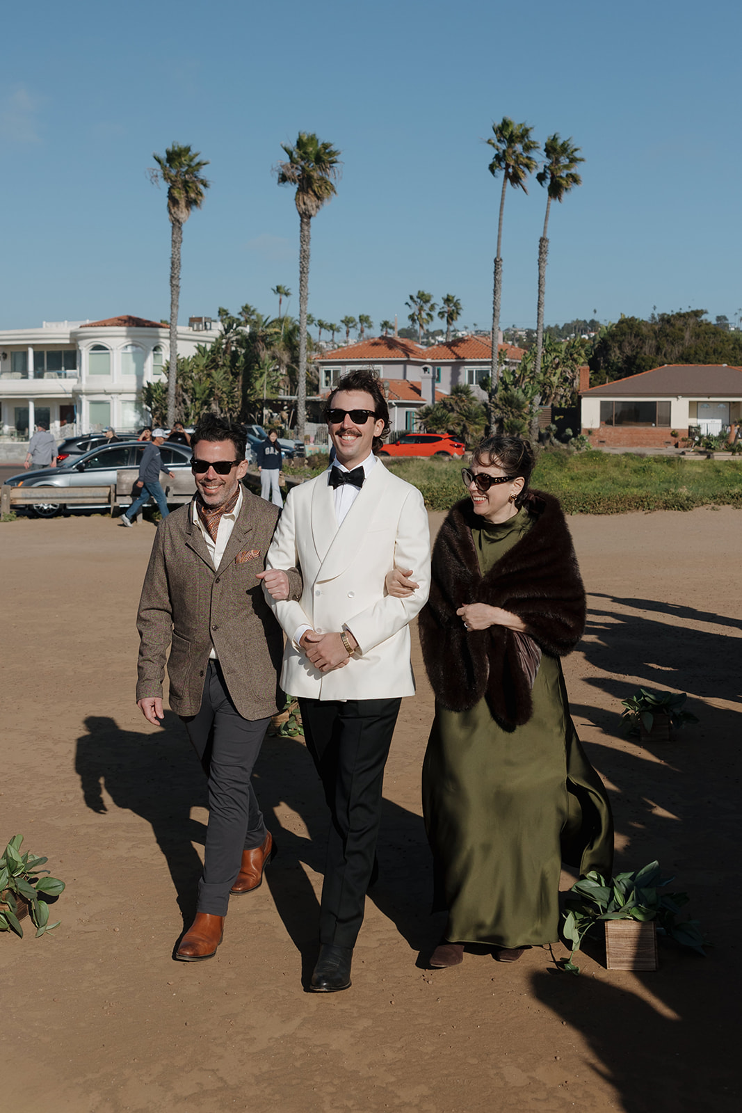 Groom walking with family before ceremony at the pearl san diego wedding with palm trees in background