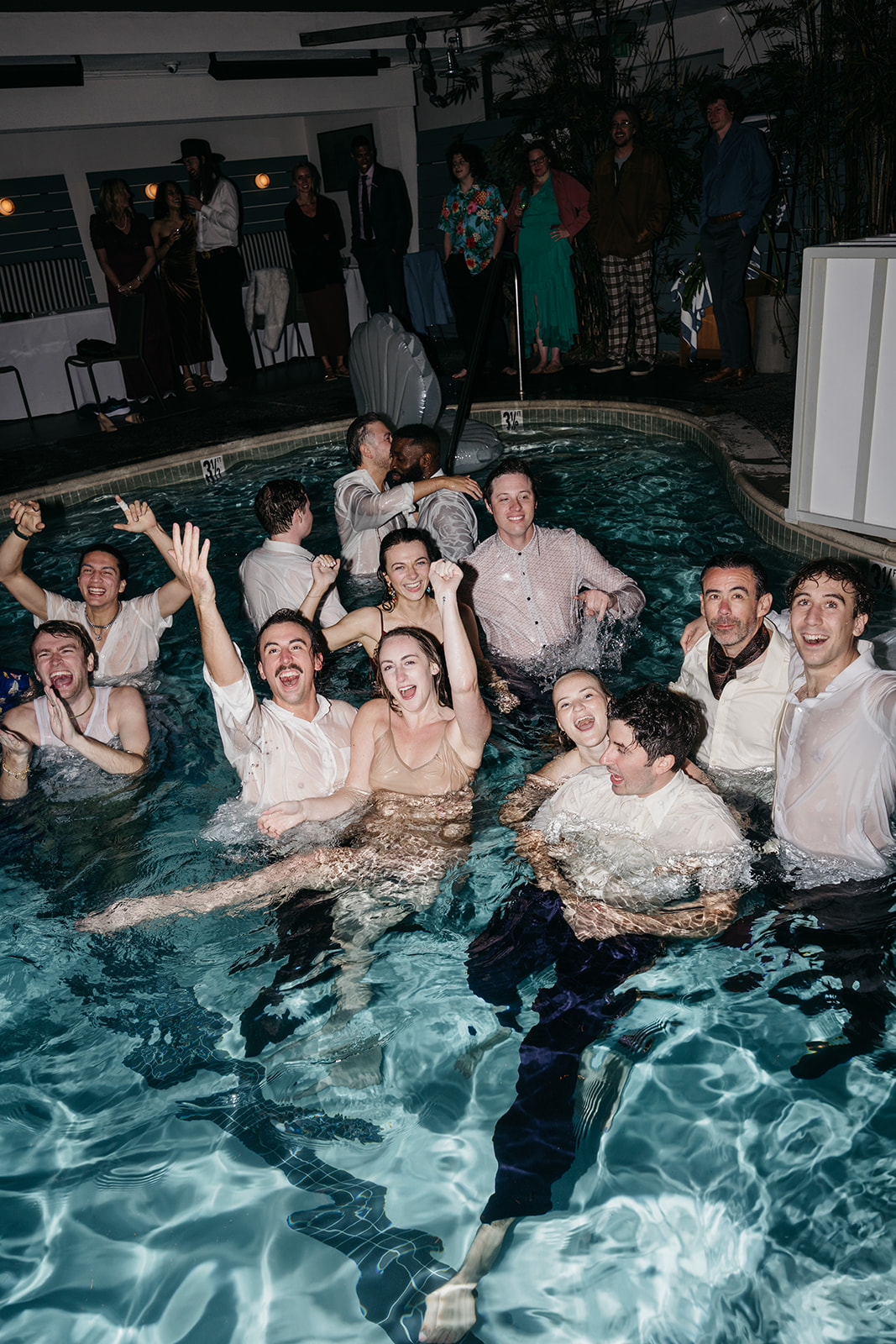 Guests jumping into pool celebrating during lively reception, candid San Diego wedding photography moment