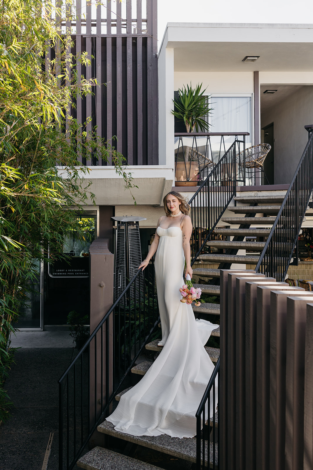 Bride walking down modern hotel staircase holding bouquet during the pearl san diego wedding