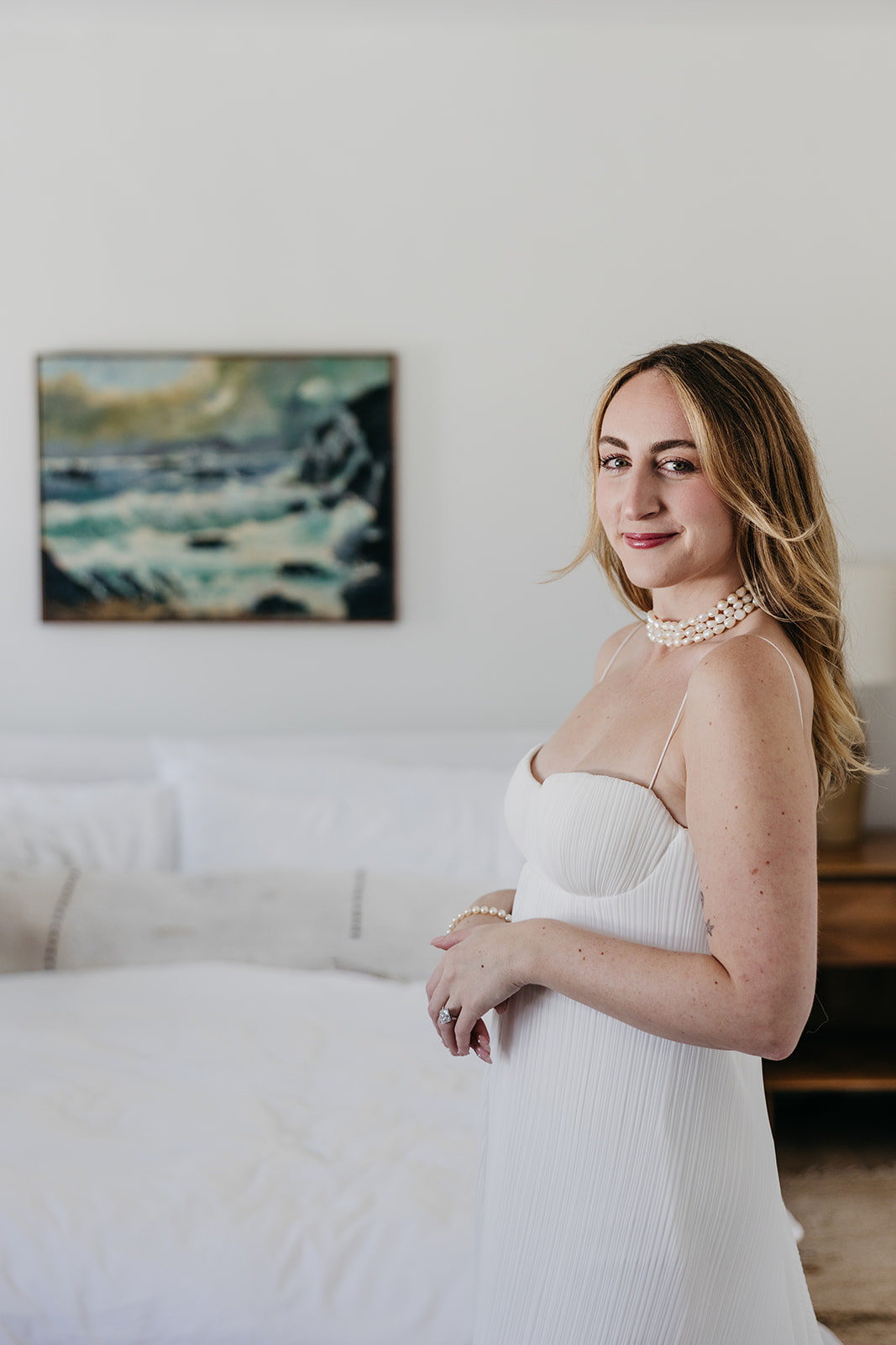 Bridal portrait in hotel room with soft light and ocean-inspired artwork in background