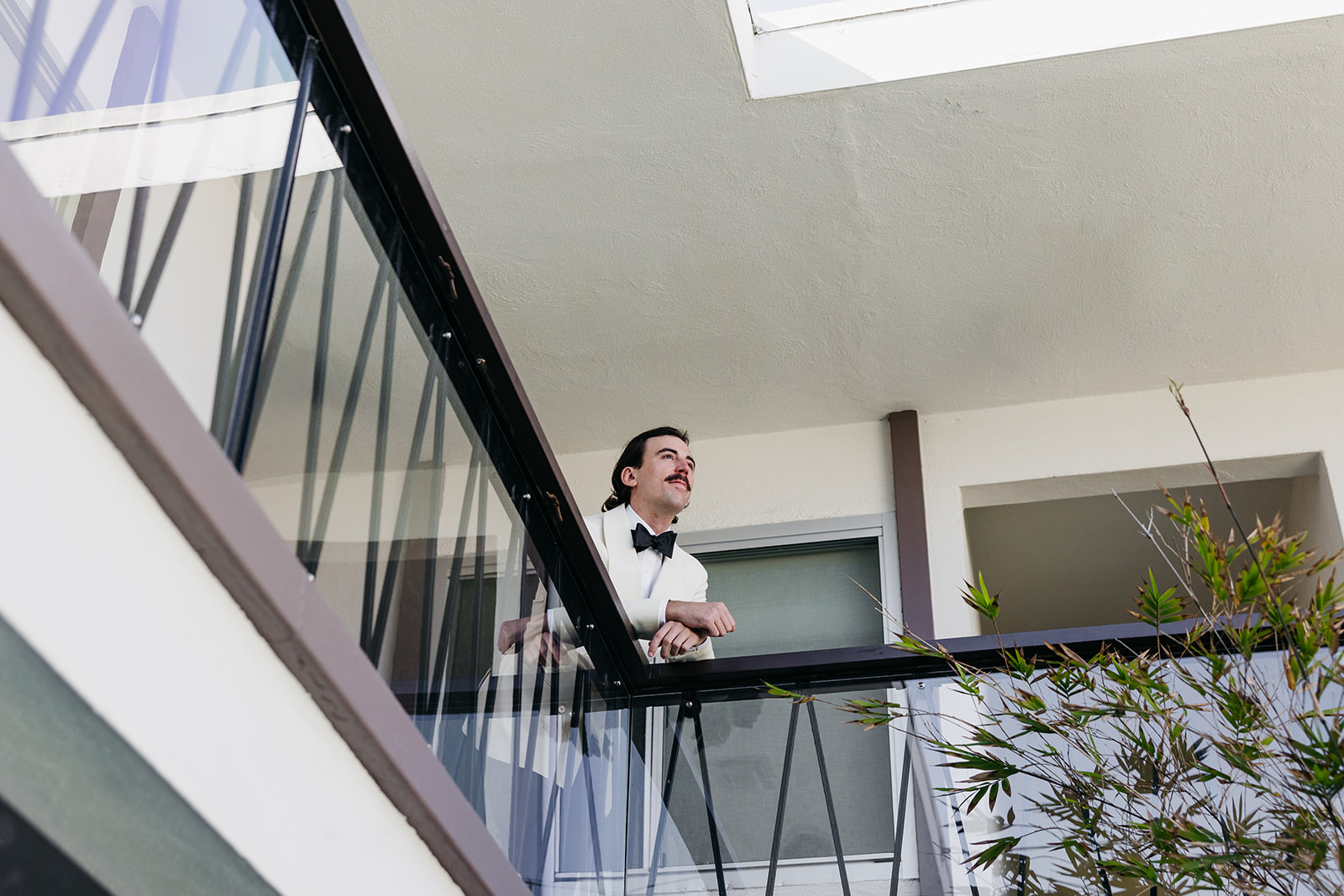 Groom leaning on balcony railing overlooking his venue in California