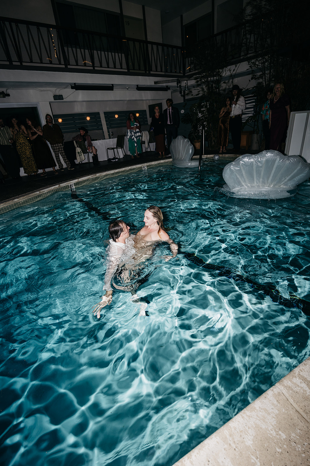 Bride and Groom embracing in pool at night, romantic and playful San Diego wedding reception scene