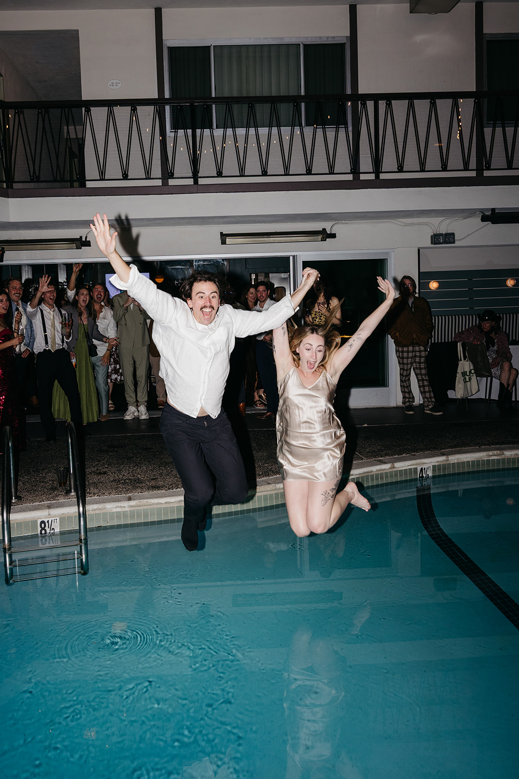 Bride and groom jumping into pool together during reception at the pearl san diego