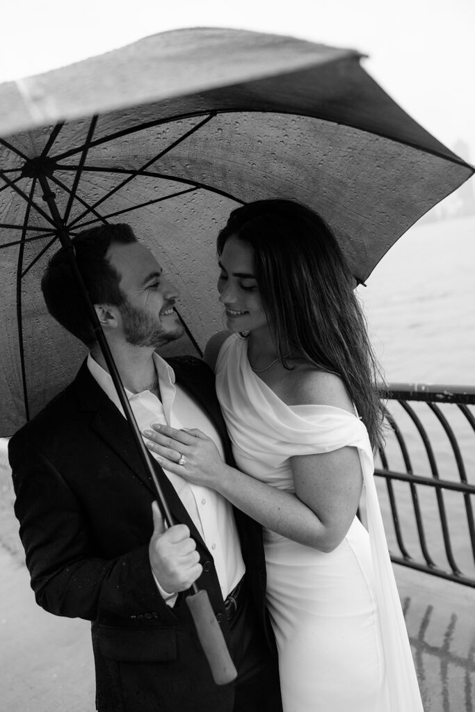 A couple under an umbrella smiling in the rain