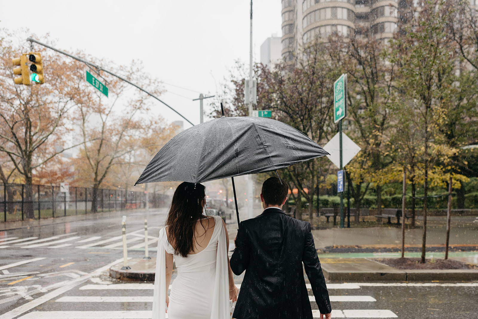 Couple holding umbrella during rainy day engagement photos in Manhattan