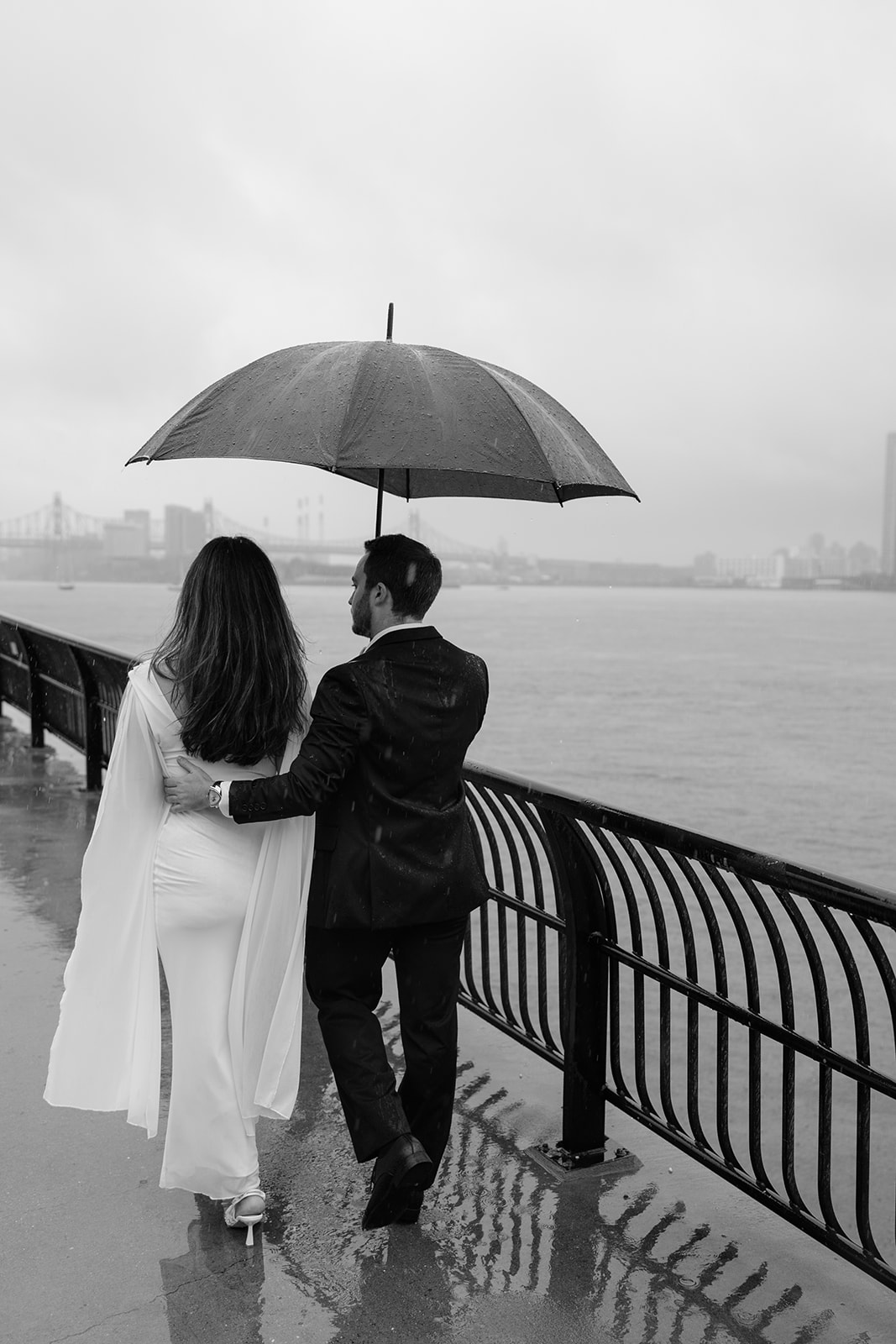 Rainy day engagement photos by the NYC waterfront with skyline views